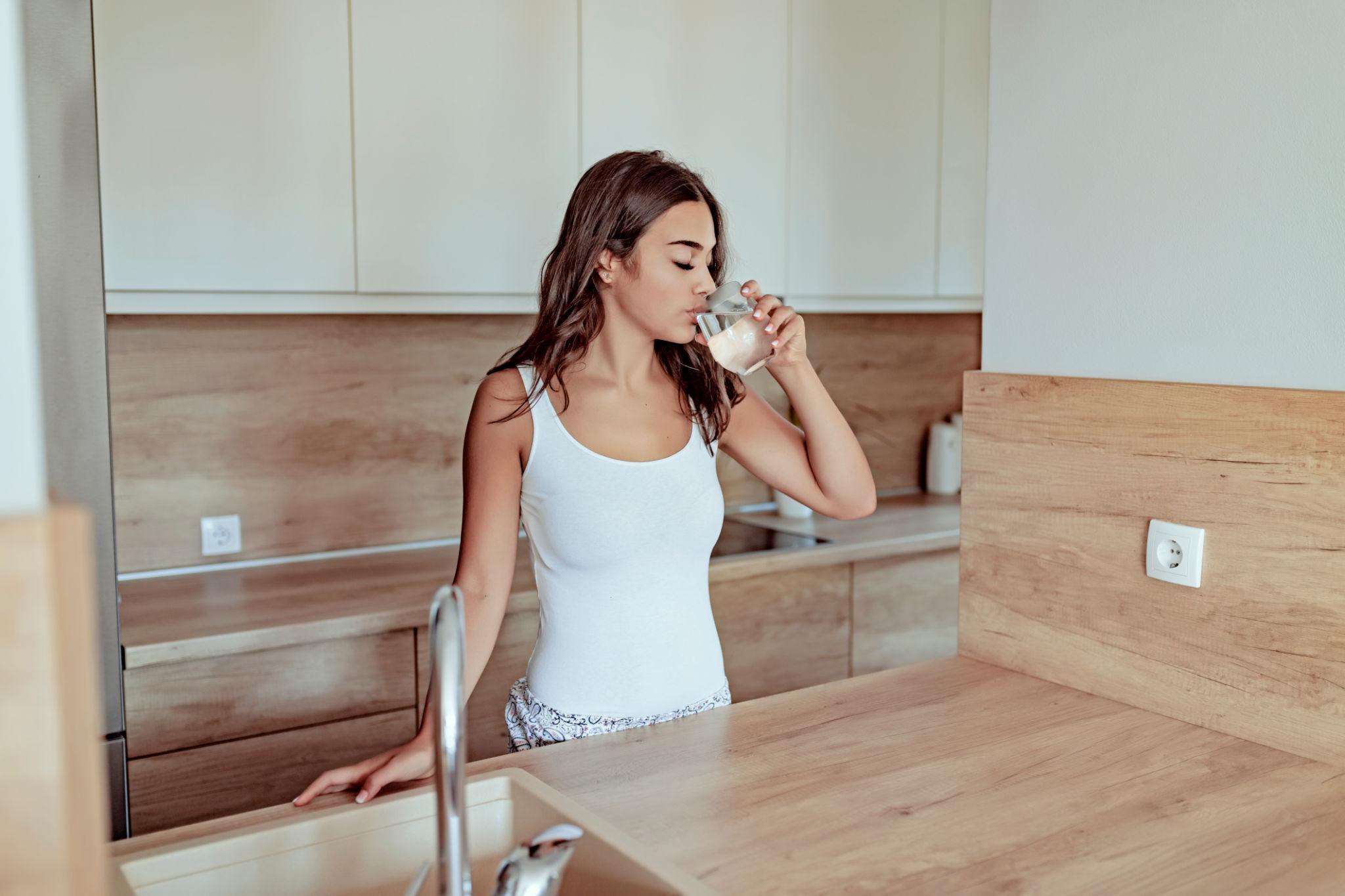 Woman drinking water in a bright modern kitchen